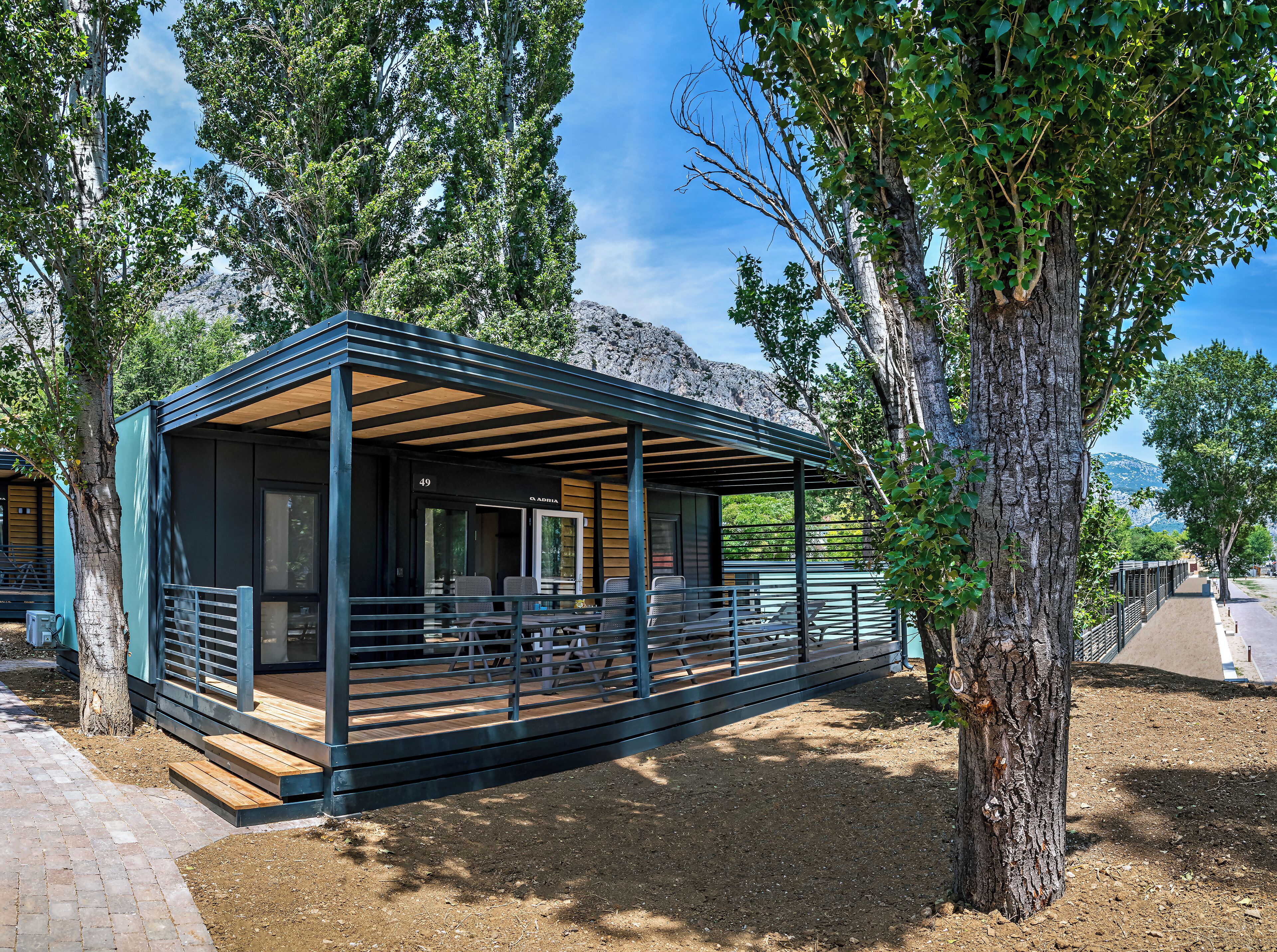 A modern, two-story building with a covered patio area, large windows, and a view of the surrounding landscape.