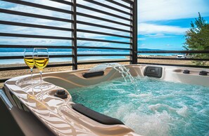 A hot tub with two glasses of wine, a view of the beach, and a wooden deck. - Camping Almissa (Omis)