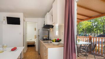 A compact kitchen with a dining area, a TV mounted on the wall, and a view of the outdoors.