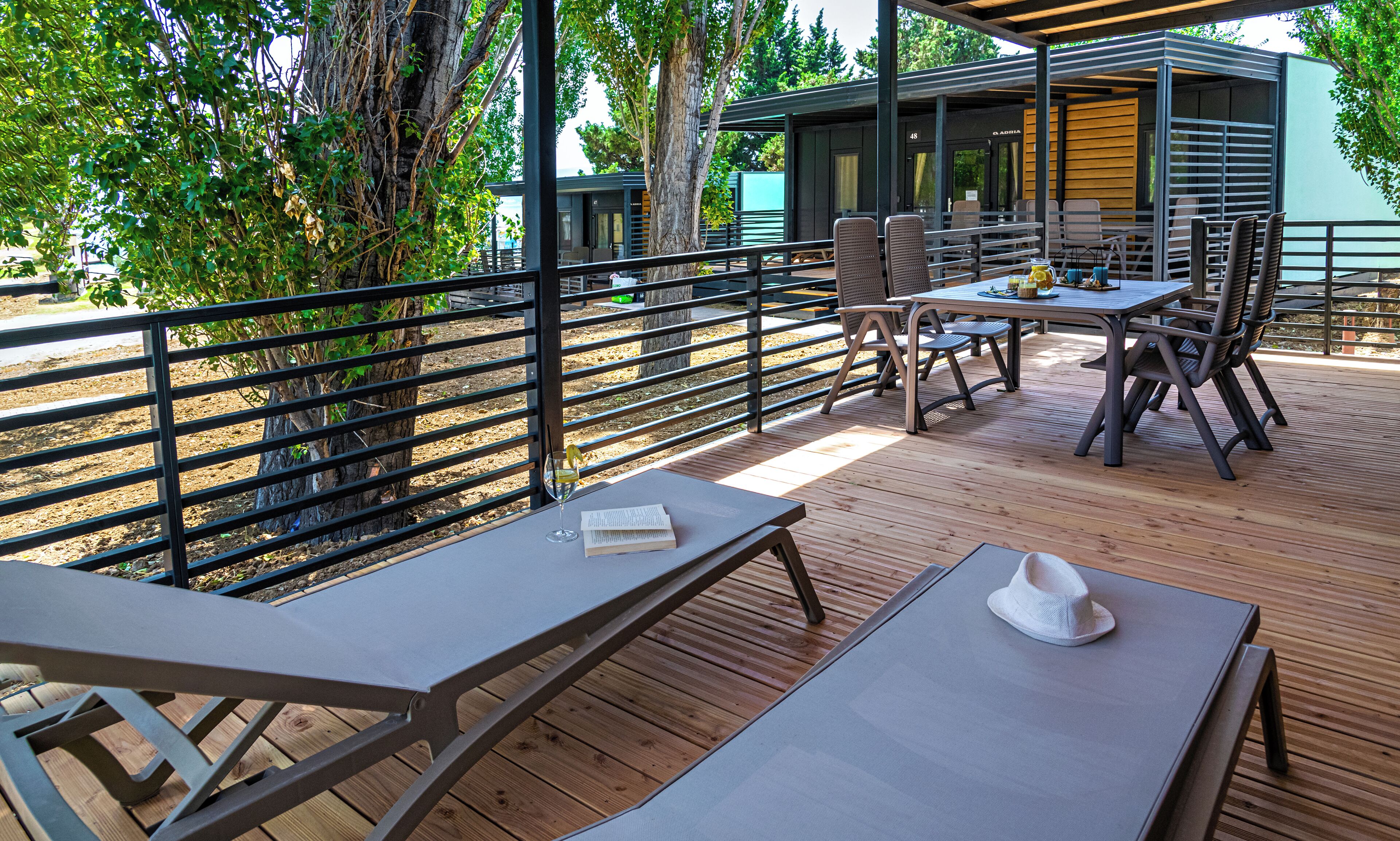 An outdoor deck with picnic tables and chairs, surrounded by a metal railing.