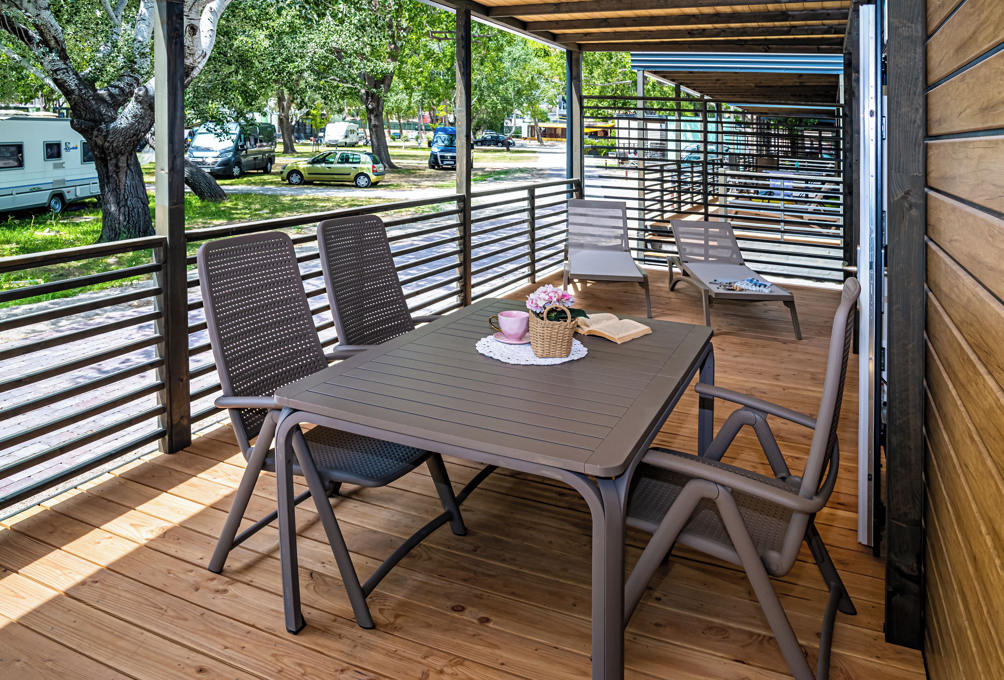 Un espacio al aire libre cubierto con una mesa, sillas, una cesta de mimbre y un libro.