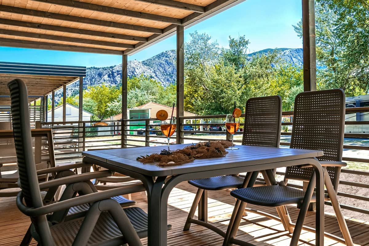 Un patio al aire libre con una mesa y sillas, con vistas a un paisaje montañoso.