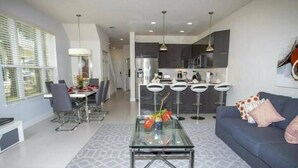 Una sala de estar moderna con una mesa de centro de vidrio, un sofá y un comedor con una mesa y sillas.
