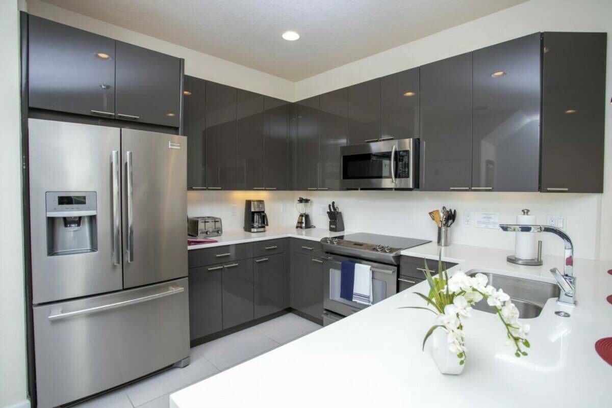 A modern kitchen with stainless steel appliances, dark cabinets, and a white countertop.