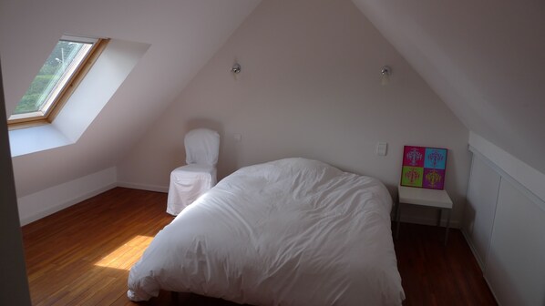 A bedroom with a sloped ceiling, a skylight, a single bed, a chair, and a colorful artwork on the wall. - Duplex Thalasso area, comfort, near beach, Tennis, Wifi & Parking included (Quiberon)