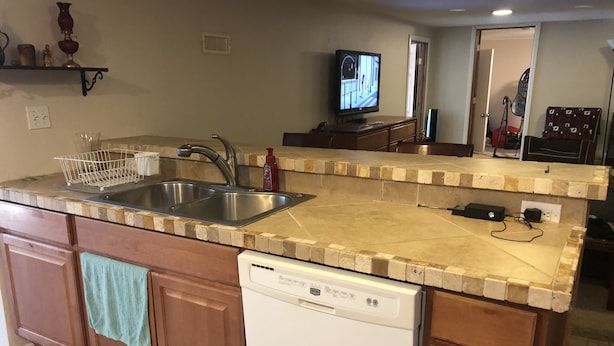 A kitchen with a built-in dishwasher, a double sink, and a television mounted on the wall. - Beautiful private 2 bedrooms/1 bathroom near campus (Boulder)