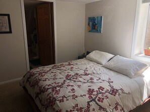 A bedroom with a bed, a nightstand, a painting, and a window with a plant. - Beautiful private 2 bedrooms/1 bathroom near campus (Boulder)