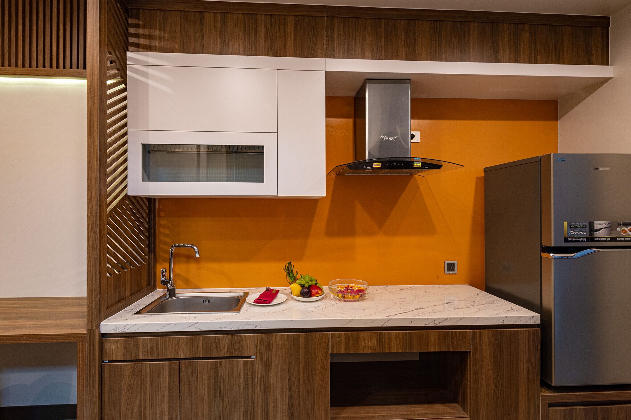 A modern kitchen with a stainless steel refrigerator, a built-in oven, and a wooden cabinet design.