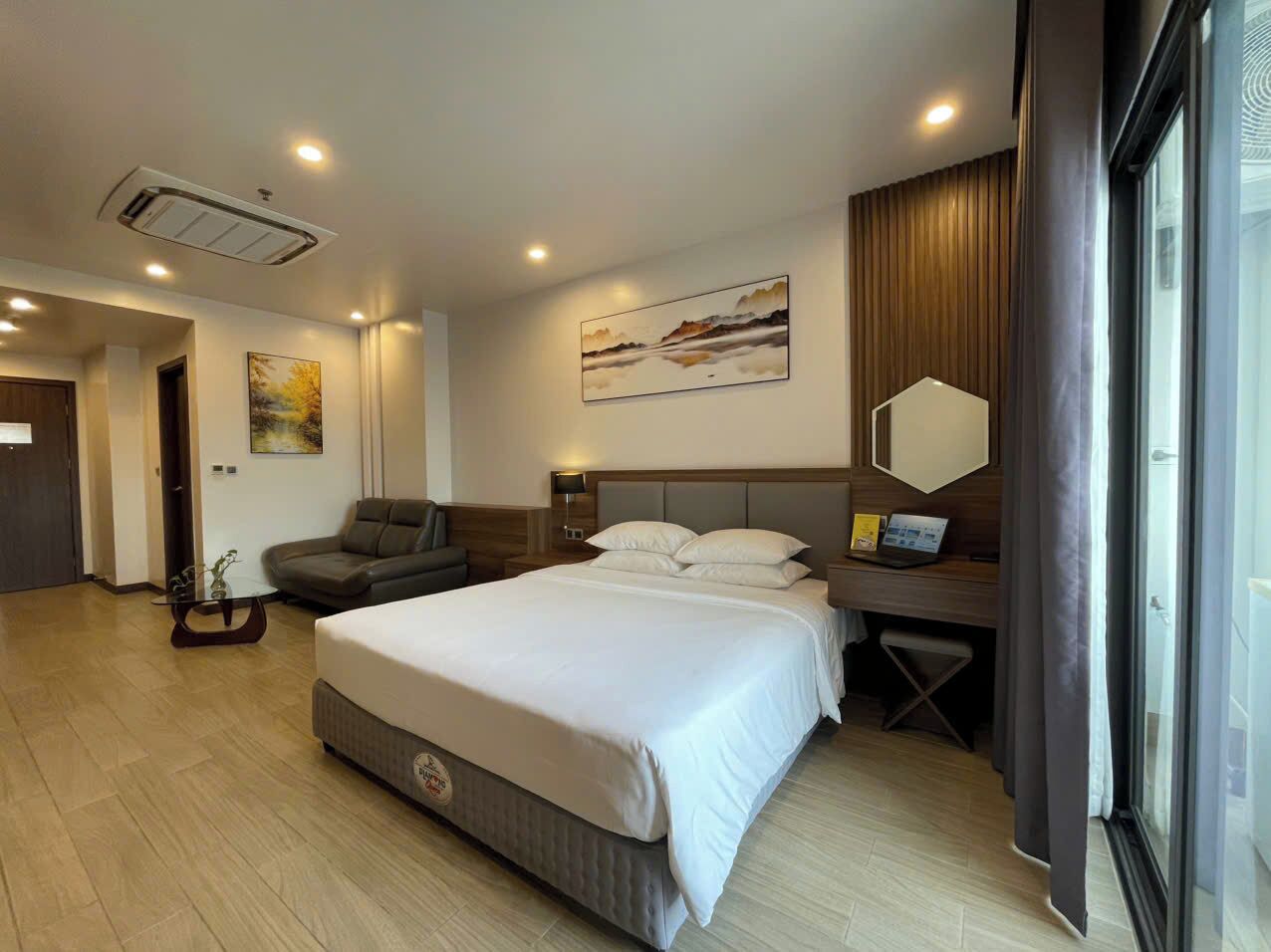 Quarto de hotel moderno com uma cama grande, uma escrivaninha, um sofá e um quadro na parede.