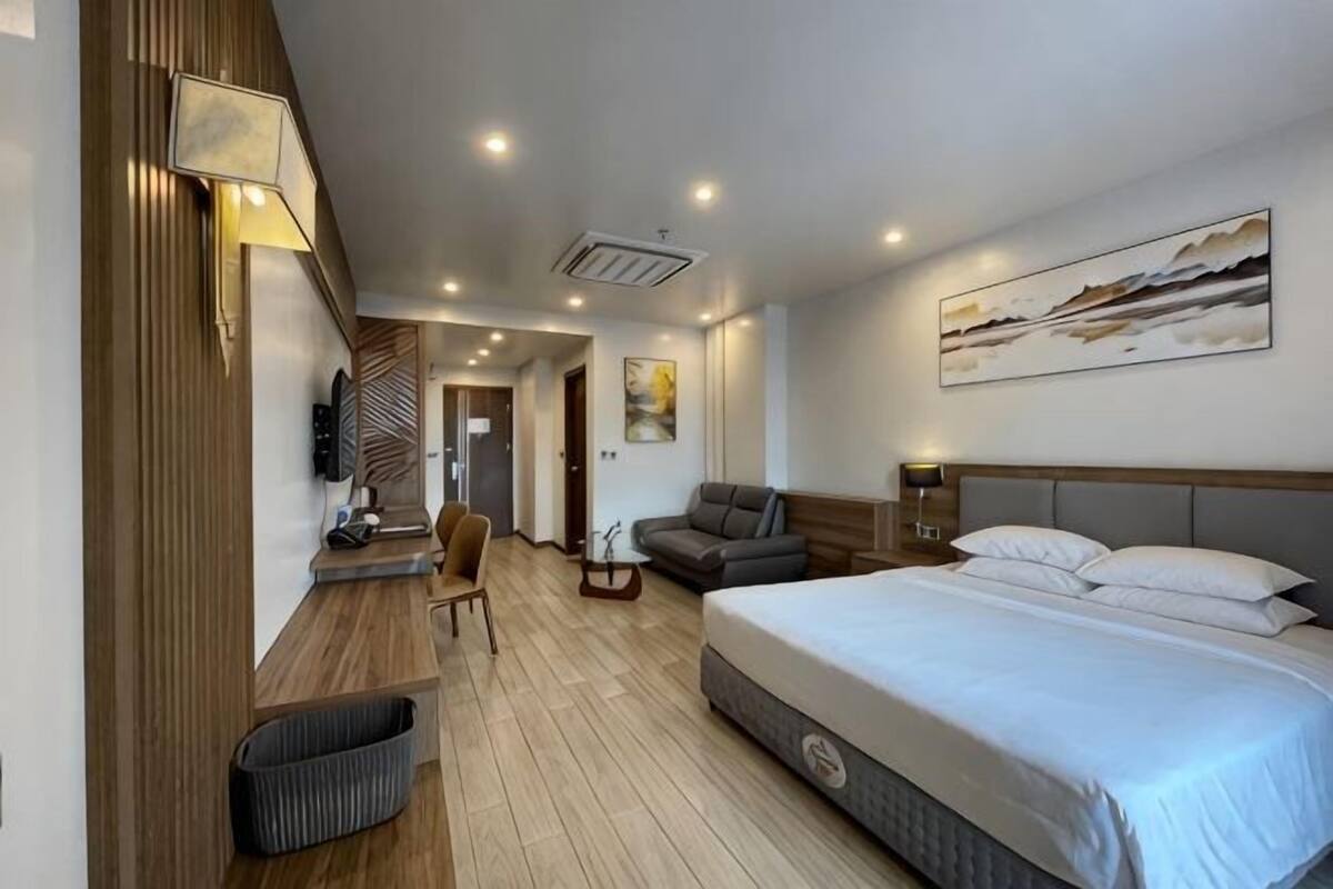 Ein Hotelzimmer mit einem Bett, einem Schreibtisch, einem Sessel, einem Fernseher und einem Bild an der Wand.
