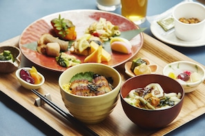 Una variedad de platos sobre una bandeja de madera, incluyendo un tazón de pescado, un tazón de fideos y varios recipientes pequeños con diferentes ingredientes.