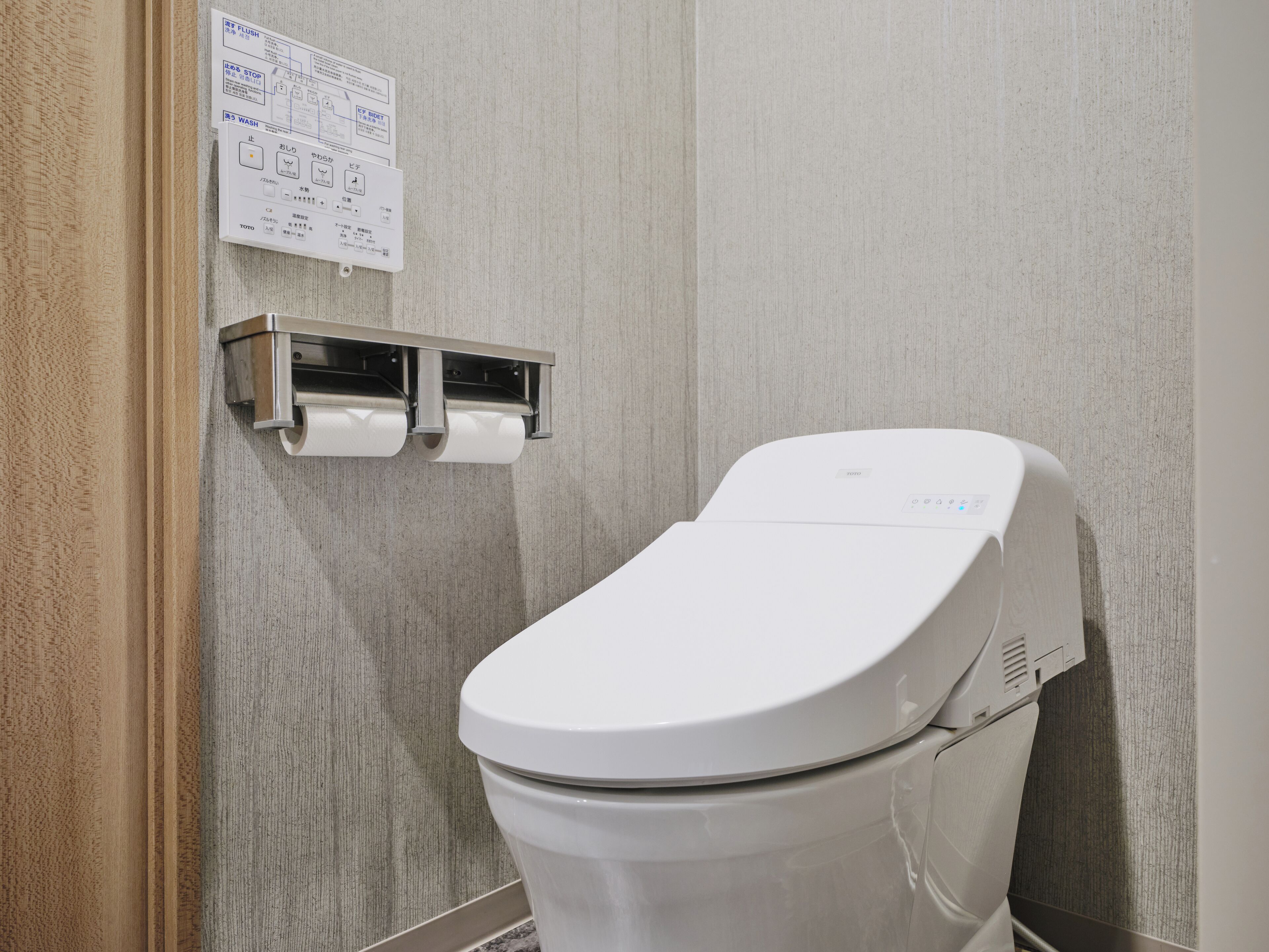 Un baño moderno con inodoro, secador de manos y dispensador de toallas de papel.