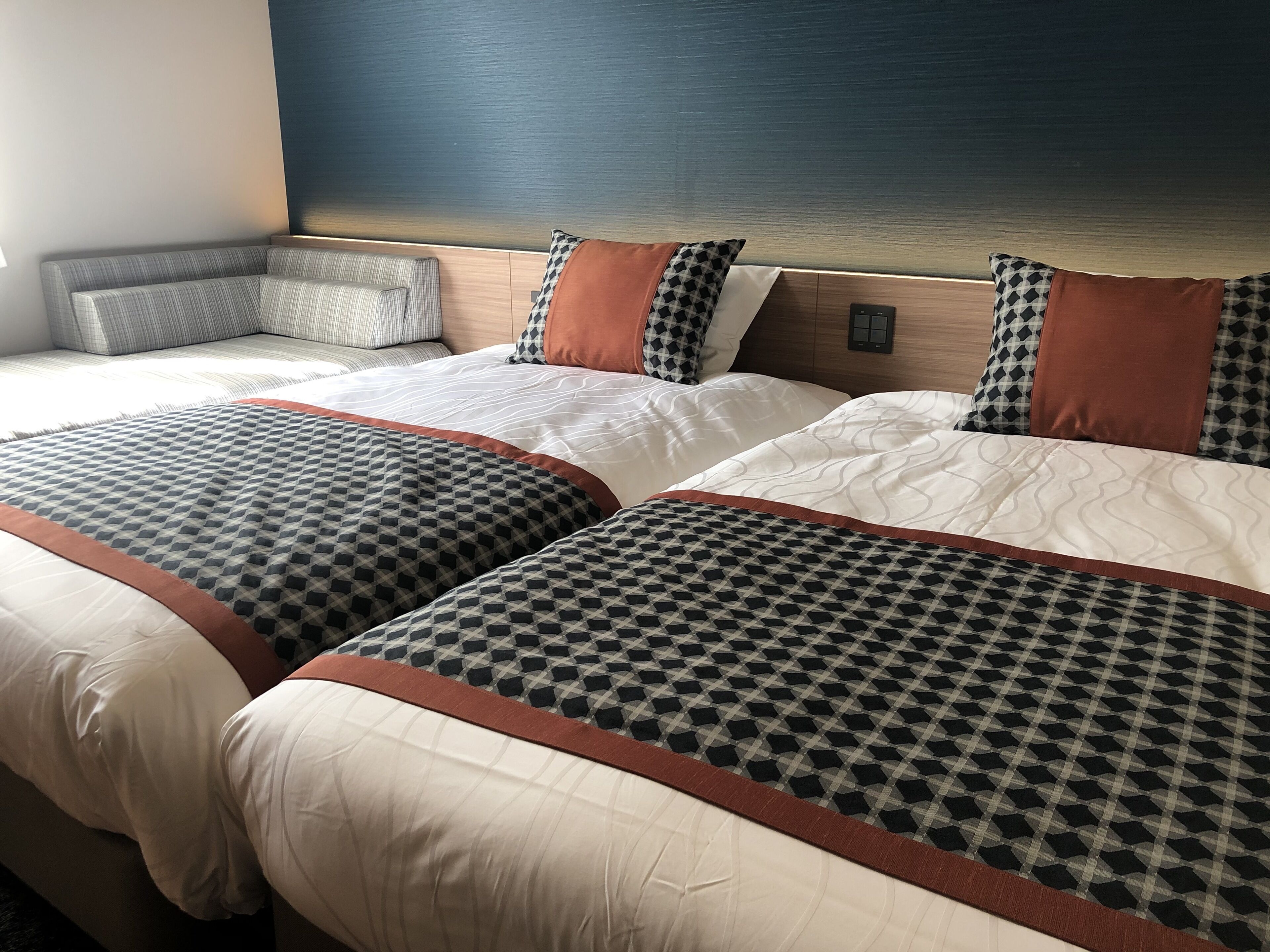 Ein Hotelzimmer mit zwei Betten, jeweils mit gemusterten Bettdecken und passenden Kissen.