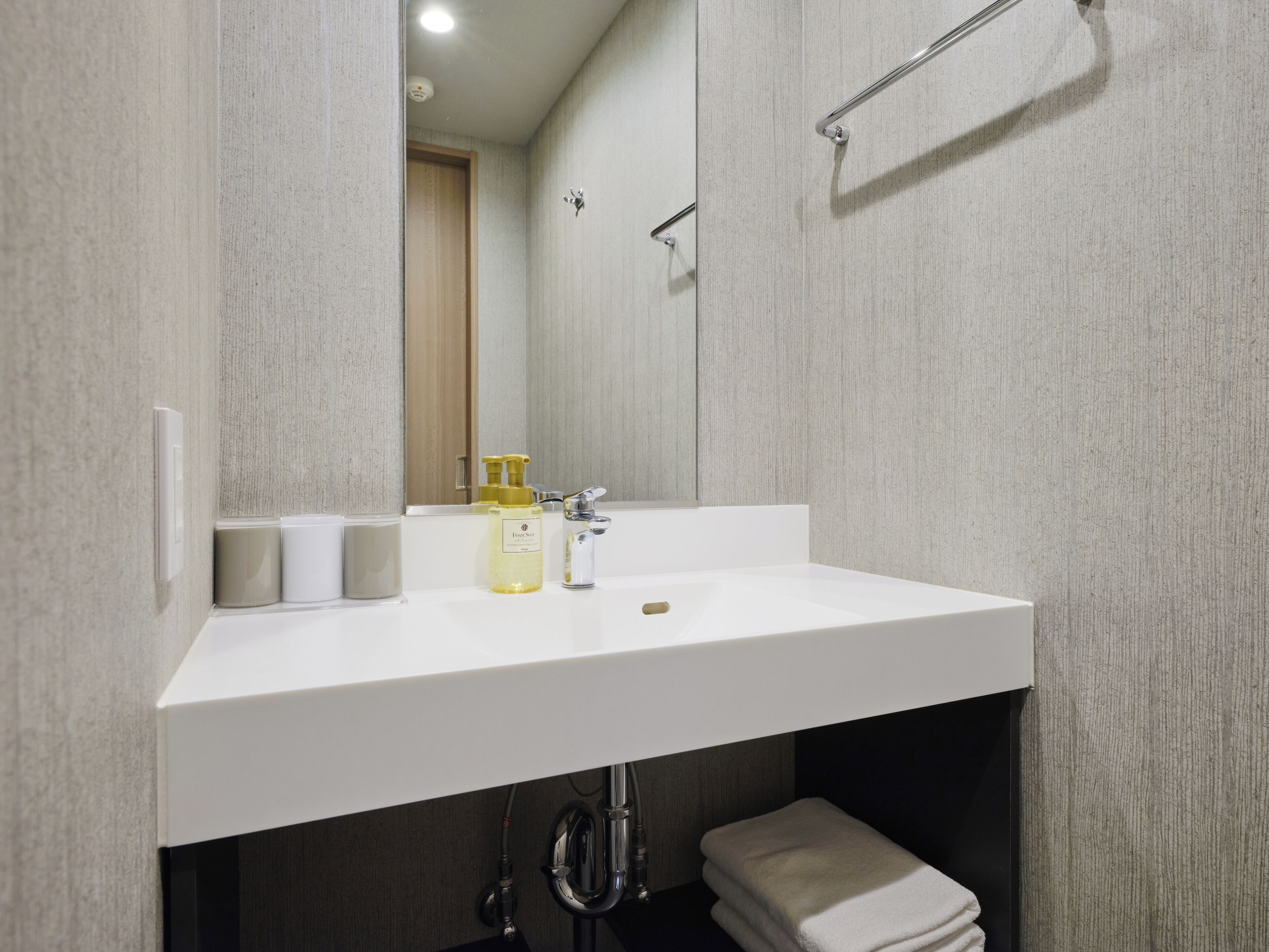 Ein modernes Badezimmer mit Waschbecken, Spiegel und Handtuchhalter.