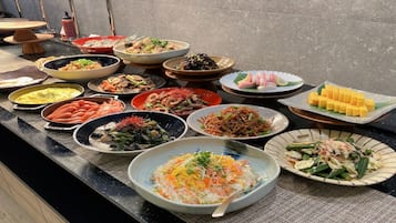 A buffet table with various dishes including rice, vegetables, and seafood.