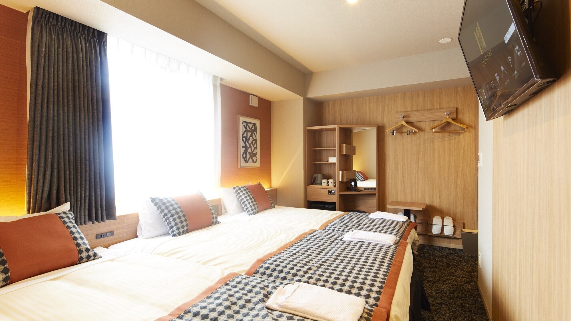 A hotel room with a large bed, a wardrobe, a TV, and a desk.