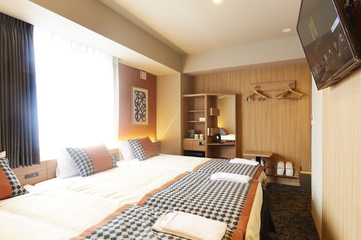 A hotel room with a large bed, a wardrobe, a TV, and a desk.