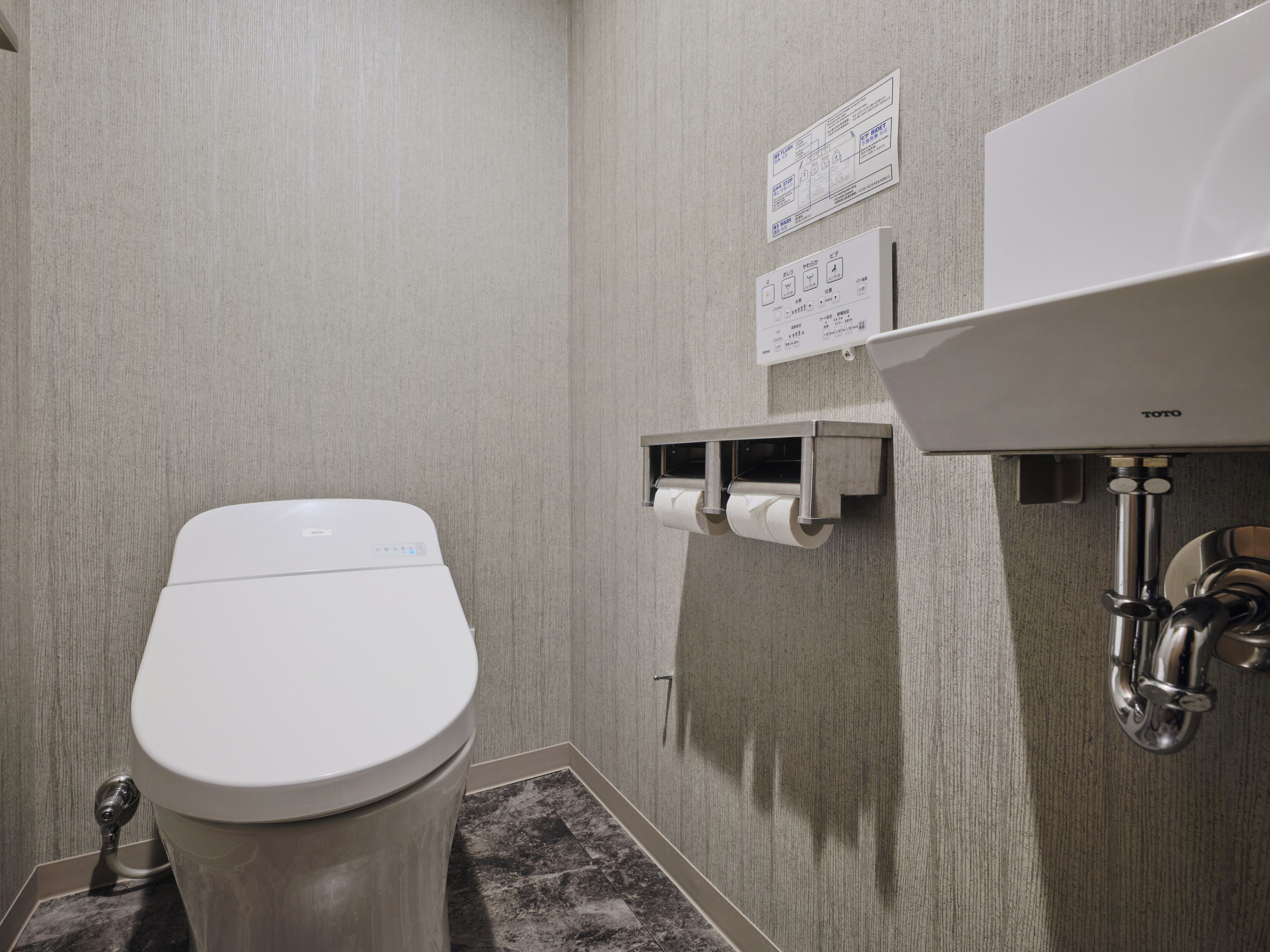 Une petite salle de bain moderne équipée de toilettes, d’un lavabo et d’un distributeur de serviettes en papier.