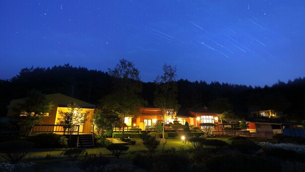 A hotel with multiple buildings, a well-lit garden, and a starry night sky. - Byeolmuri Pension (Hoengseong)