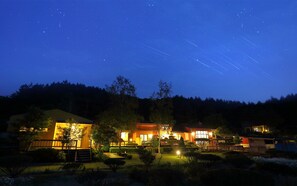 A hotel with multiple buildings, a well-lit garden, and a starry night sky. - Byeolmuri Pension (Hoengseong)