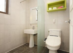 Un baño con un lavamanos blanco, un inodoro y un estante verde sobre el inodoro.
