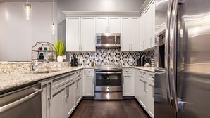 Una cocina moderna con electrodomésticos de acero inoxidable, armarios blancos y encimera de mármol.