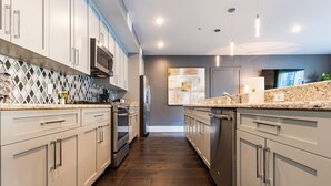 A modern kitchen with white cabinets, a granite countertop, and a stainless steel refrigerator. - ⚜️Stylish,Spacious & Comfortable Downtown Penthouse! Enjoy The View from Your Personal Terrace! (New Orleans)