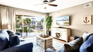 A modern living room with a sofa, coffee table, TV, and a balcony with a view.