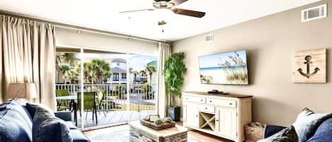A modern living room with a sofa, coffee table, TV, and a balcony with a view.