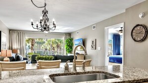 A modern kitchen with granite countertops, stainless steel sink, and a chandelier.