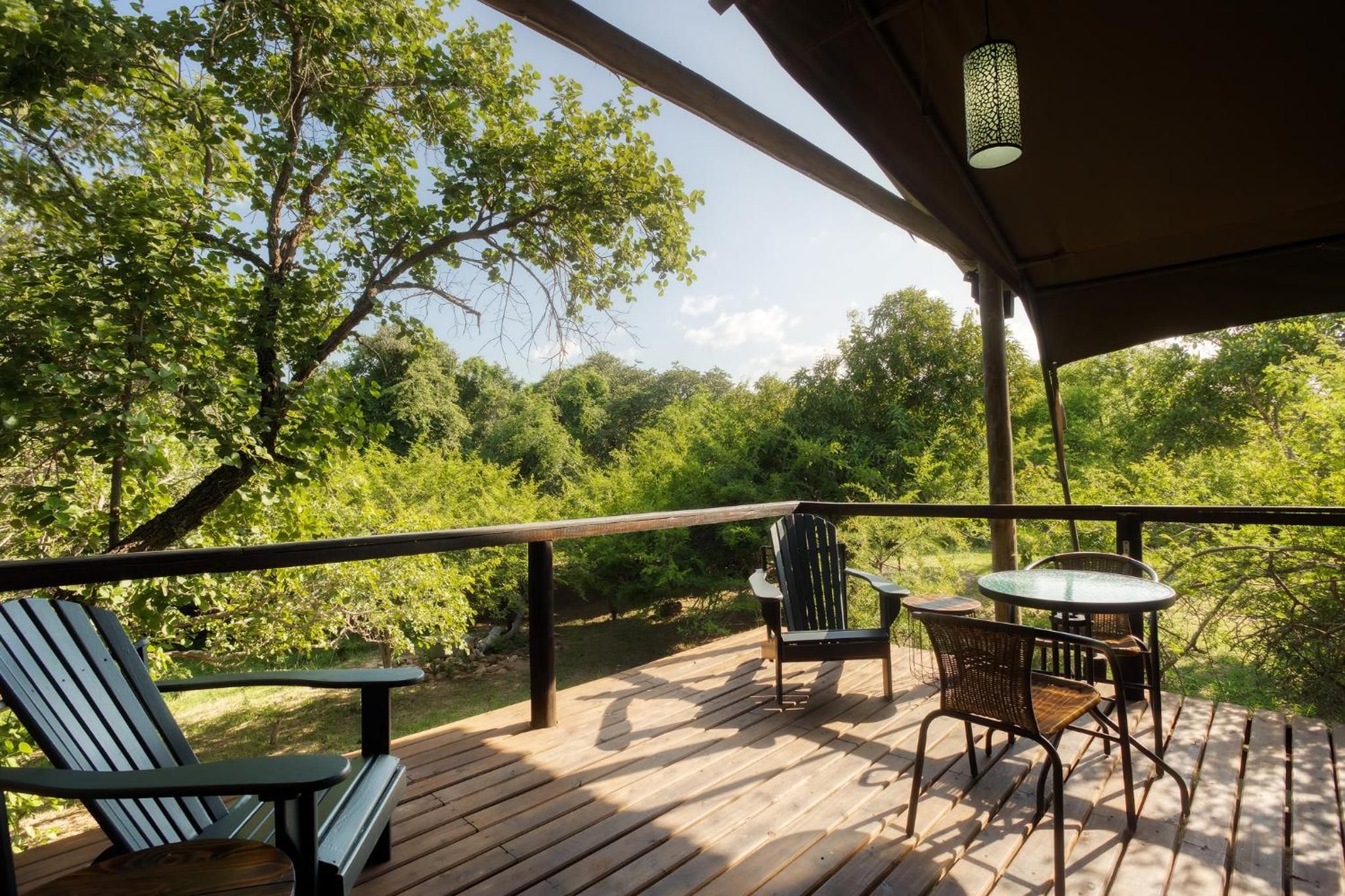 An outdoor deck with a table and chairs, surrounded by trees.