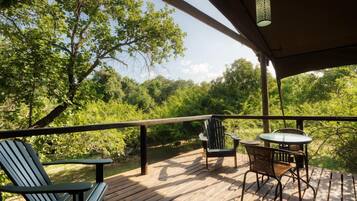An outdoor deck with a table and chairs, surrounded by trees.