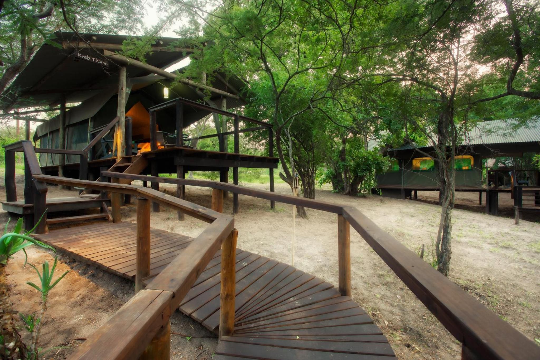 Une terrasse en bois menant à un chalet, avec un escalier en métal.
