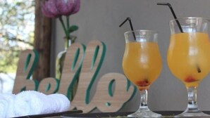 Zwei Orangensaftgläser mit Strohhalmen auf einer Tablett, ein Holzschild mit dem Wort 'Belle' und ein weißes Handtuch.