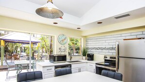 A modern kitchen with a dining area, featuring a stainless steel refrigerator, microwave, and oven. - 3BR Captiva Cottage with Hot Tub & Steps to the Beach (Captiva)