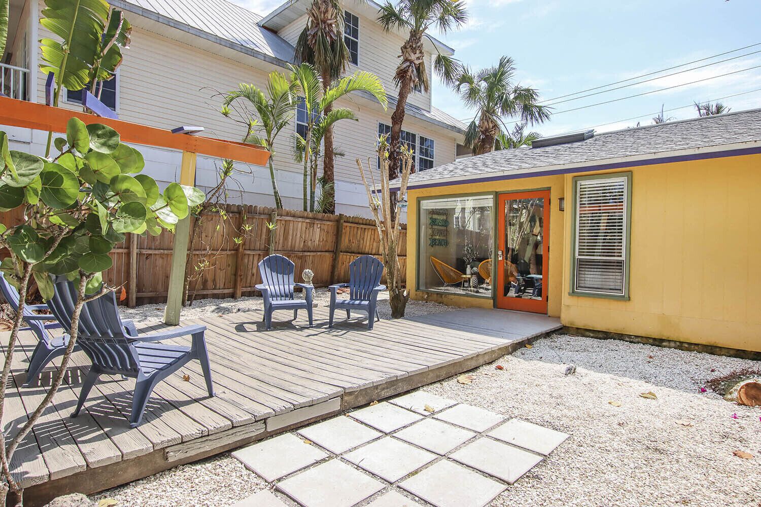 A patio with two Adirondack chairs, a small table, and a wooden deck.