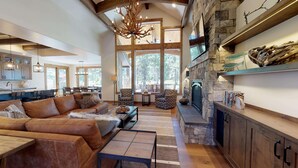 A spacious living area with a leather sofa, a stone fireplace, and a dining area with wooden chairs.