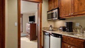 A compact kitchen with wooden cabinets, a microwave, a coffee maker, and a dishwasher. - Grand Lodge Peak 7 Suite (Breckenridge)