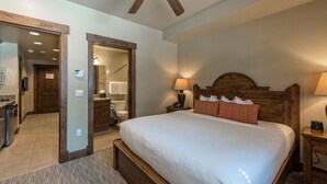 A bedroom with a large bed, wooden headboard, bedside lamp, and a wooden nightstand. - Grand Lodge Peak 7 Suite (Breckenridge)