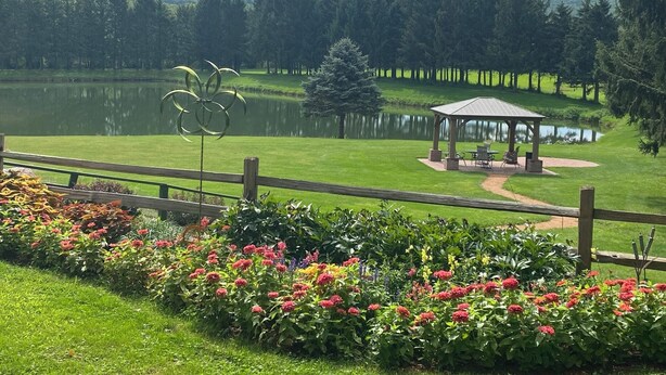 Un campo de golf con un pabellón, un estanque y una valla de madera.