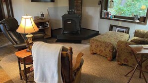 Una sala de estar acogedora con chimenea, televisor montado en la pared y un espacio de descanso cómodo con mesa y sillas.