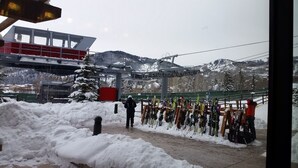 A ski resort with a ski lift, snow-covered trees, and a row of skis and snowboards.