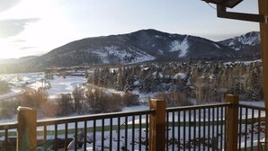 A snowy mountain landscape with a view of a valley and a building with a snow-covered roof.