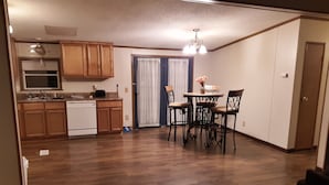 A compact kitchen with wooden cabinets, a white refrigerator, and a dining area with a table and four chairs.