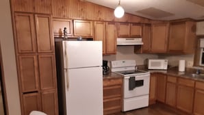 A kitchen with wooden cabinets, a white refrigerator, a stove, and a microwave.
