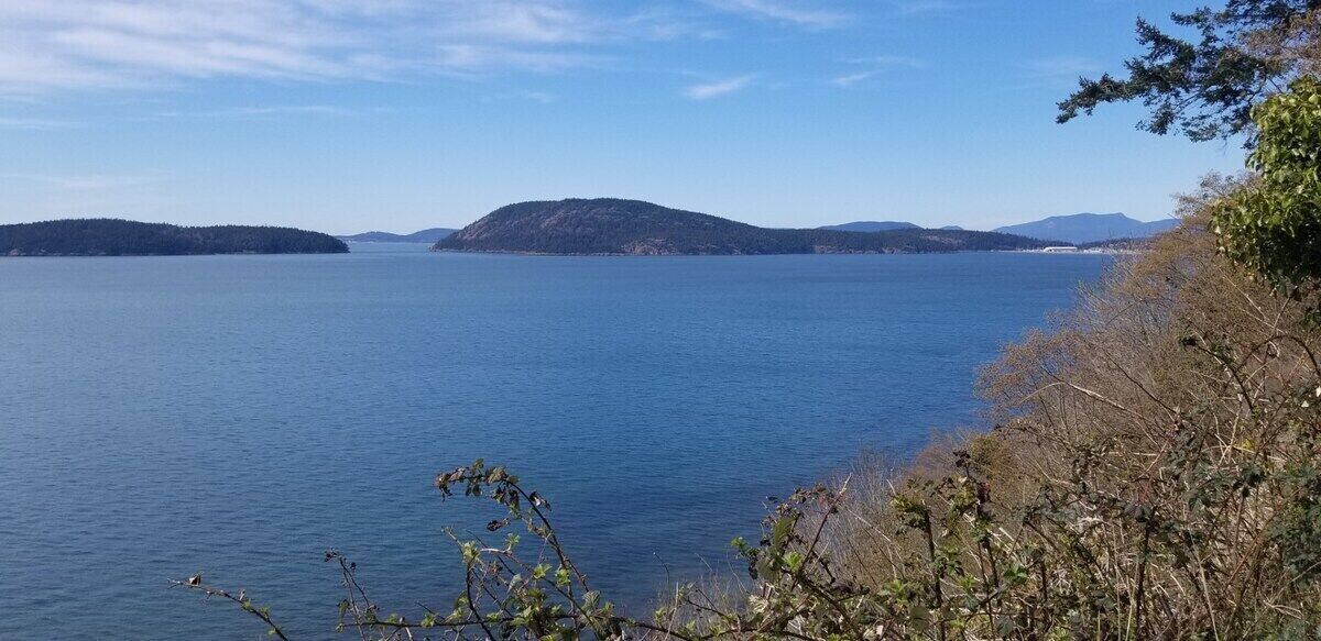 Ein ruhiger See mit fernen Inseln und einem klaren Himmel.