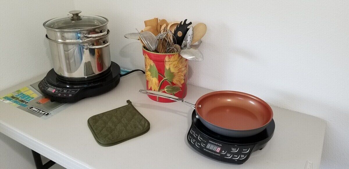 A kitchen counter with a blender, a pot, a pan, and a utensil holder.