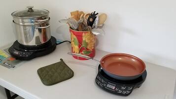 A kitchen counter with a blender, a pot, a pan, and a utensil holder.