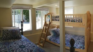 Un dormitorio con dos literas, una escalera y una ventana que da a vistas del exterior.
