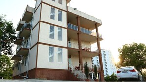 A multi-story residential building with balconies, a staircase, and a parked car. - Tamara bed and breakfast :-) (Batumi)